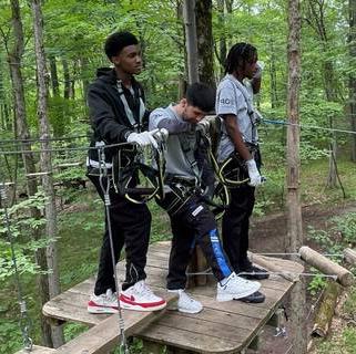 Teambuilding exercise with 3 EOP students standing on zip line platform waiting to go next.
